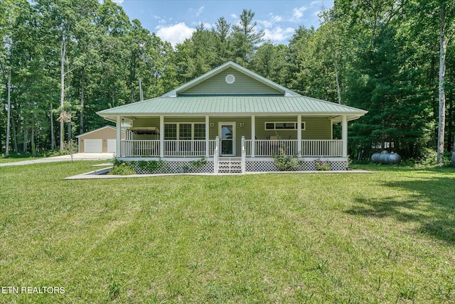 farmhouse inspired home with a porch, a front lawn, a garage, and an outdoor structure