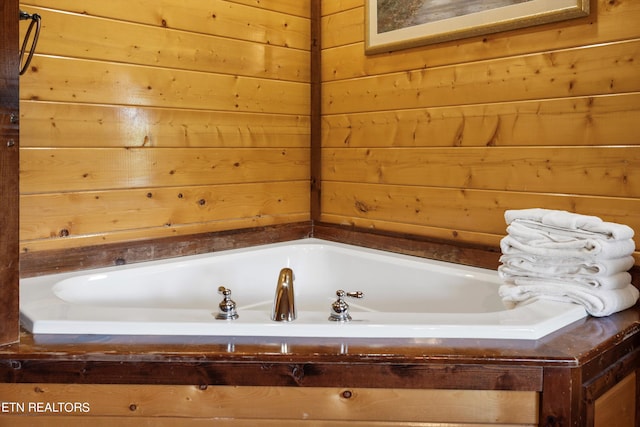 bathroom with a bath and wood walls