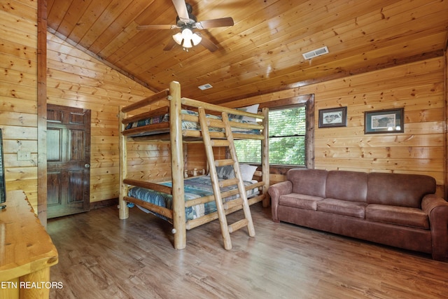 bedroom featuring wood ceiling, ceiling fan, wooden walls, wood-type flooring, and lofted ceiling