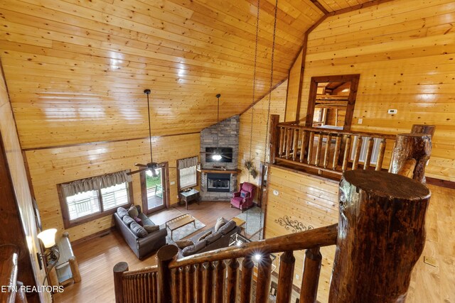 living room with wood walls, ceiling fan, wooden ceiling, and light hardwood / wood-style floors