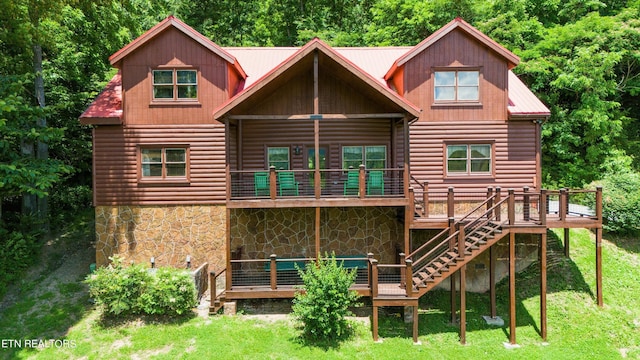 back of property featuring a wooden deck and a yard