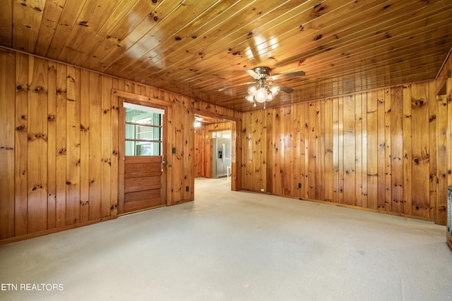 spare room featuring carpet, wooden walls, and ceiling fan