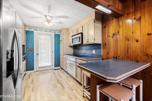 kitchen featuring a breakfast bar area, ceiling fan, light hardwood / wood-style flooring, and appliances with stainless steel finishes