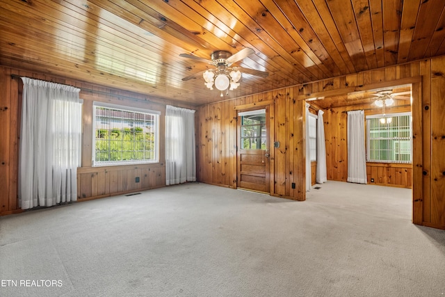 unfurnished room with ceiling fan, light colored carpet, wood walls, and wooden ceiling