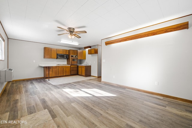 unfurnished living room featuring radiator, light hardwood / wood-style flooring, and ceiling fan