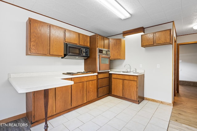 kitchen featuring sink, black appliances, and light hardwood / wood-style floors