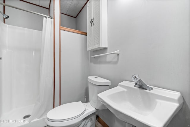 bathroom featuring toilet, sink, and a shower with shower curtain