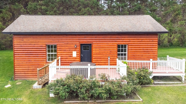 cabin with a front yard and a deck