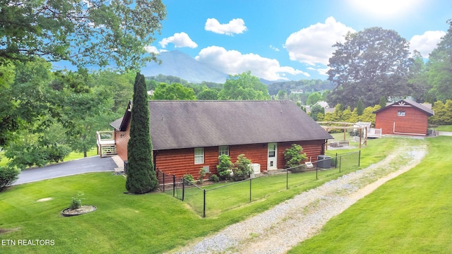 view of side of home with a mountain view, an outbuilding, and a yard