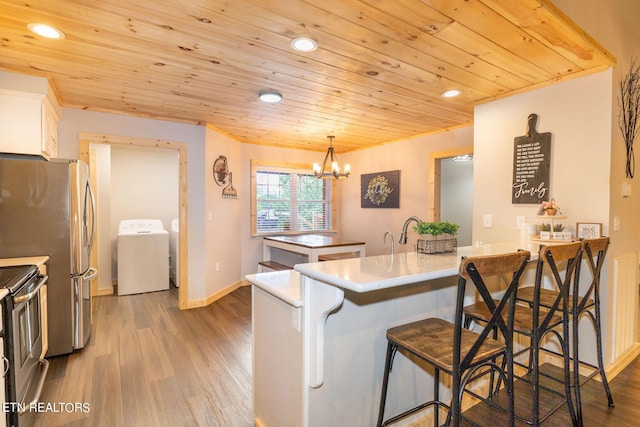 kitchen featuring electric range oven, kitchen peninsula, pendant lighting, a breakfast bar, and white cabinets