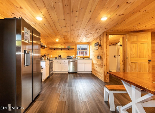 kitchen featuring stainless steel appliances, dark wood-type flooring, wooden walls, wooden ceiling, and white cabinetry