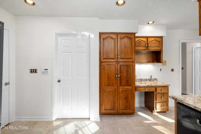 kitchen featuring light stone countertops and black dishwasher