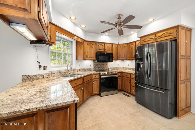 kitchen with kitchen peninsula, light stone countertops, stainless steel appliances, ceiling fan, and sink