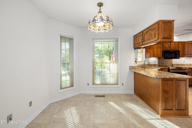 kitchen with stainless steel range with electric cooktop, sink, decorative light fixtures, light stone counters, and kitchen peninsula