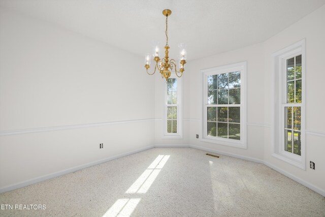 spare room featuring carpet floors and a notable chandelier