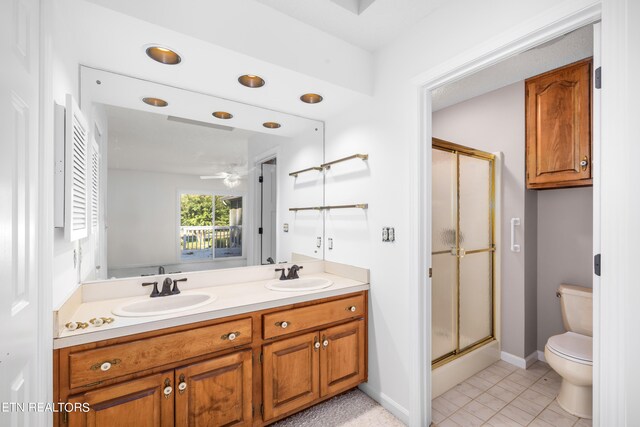 bathroom with vanity, a shower with door, ceiling fan, tile patterned flooring, and toilet