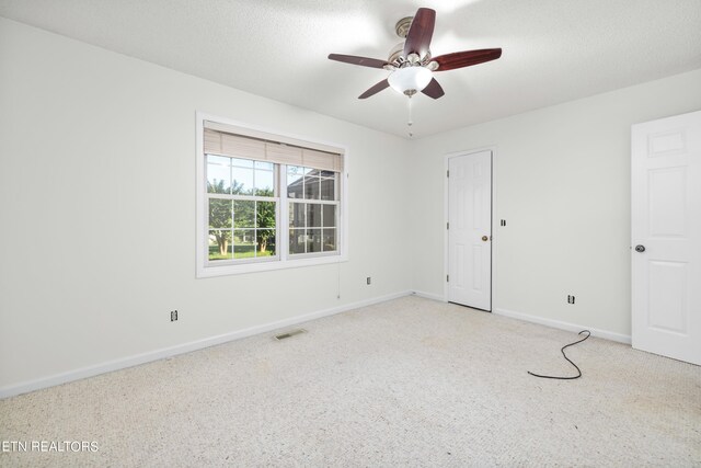 empty room with ceiling fan and a textured ceiling