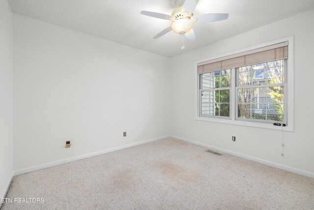 carpeted empty room featuring ceiling fan and a textured ceiling