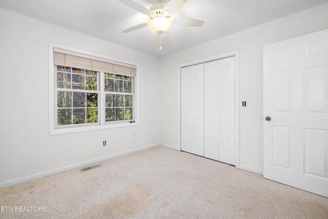 unfurnished bedroom featuring ceiling fan, a closet, and light colored carpet