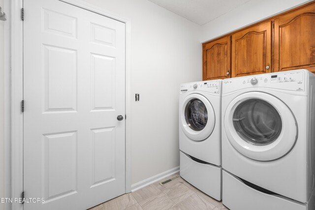 clothes washing area with washer and dryer and cabinets