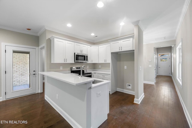 kitchen with kitchen peninsula, white cabinets, appliances with stainless steel finishes, ornamental molding, and dark hardwood / wood-style floors