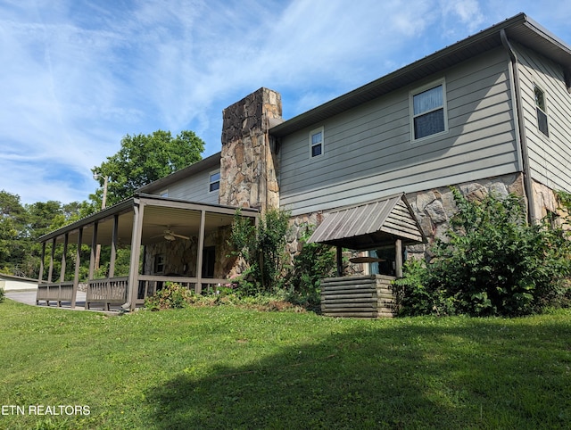 back of house featuring ceiling fan and a yard