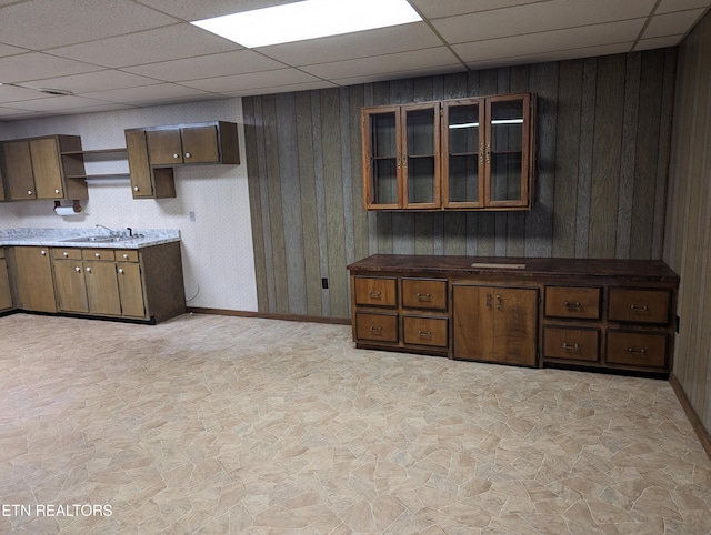 kitchen with dark brown cabinets, wood walls, and sink