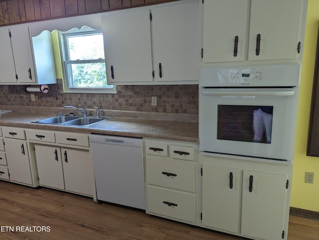 kitchen with white appliances, white cabinetry, sink, backsplash, and light hardwood / wood-style flooring