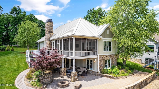 back of house with a lawn, a sunroom, a patio area, and an outdoor living space with a fire pit