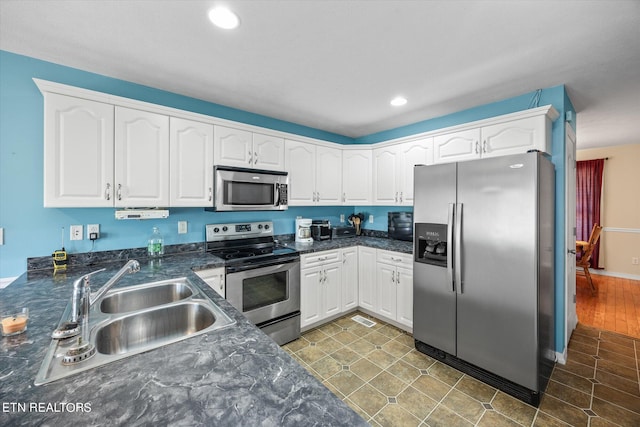 kitchen featuring dark tile patterned flooring, appliances with stainless steel finishes, sink, and white cabinetry