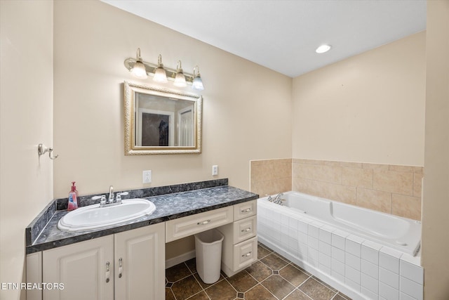 bathroom featuring tile patterned flooring, a relaxing tiled tub, and vanity