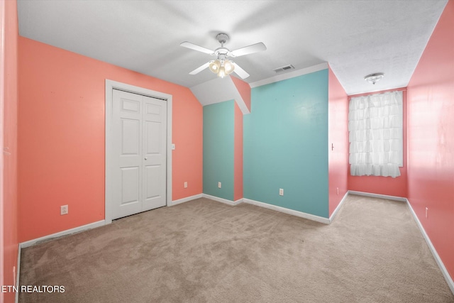 unfurnished bedroom featuring ceiling fan, light colored carpet, a closet, and vaulted ceiling