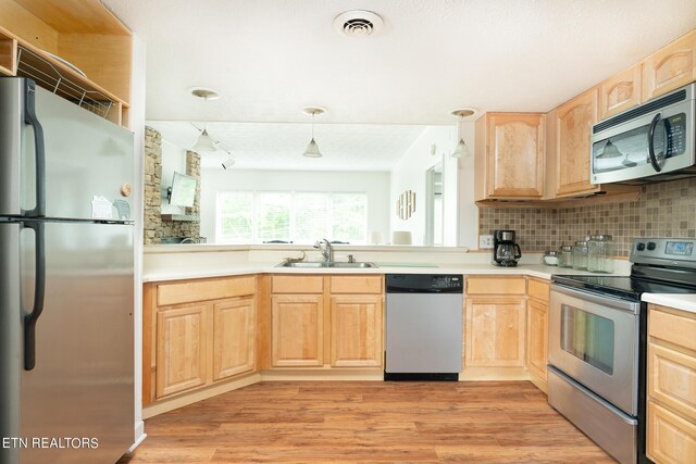 kitchen featuring appliances with stainless steel finishes, light hardwood / wood-style flooring, backsplash, sink, and light brown cabinetry