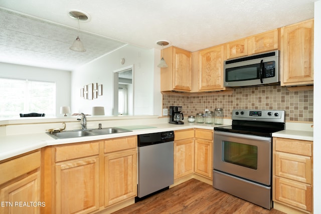 kitchen featuring pendant lighting, light brown cabinetry, appliances with stainless steel finishes, hardwood / wood-style flooring, and sink