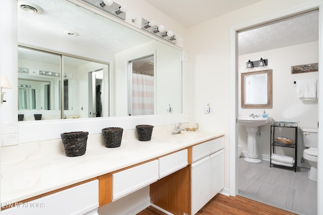 bathroom with sink, wood-type flooring, a textured ceiling, and toilet