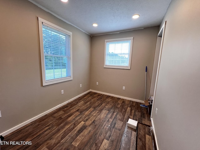 spare room featuring dark wood-type flooring and a textured ceiling