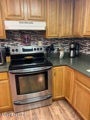 kitchen featuring stainless steel range with electric stovetop, light hardwood / wood-style floors, and backsplash