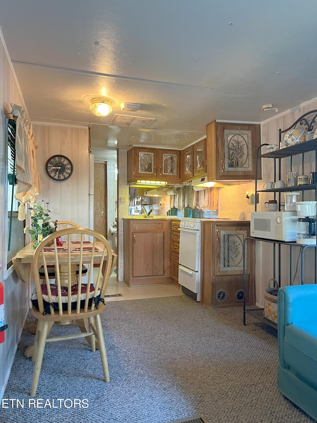 kitchen featuring crown molding, wood walls, white appliances, and carpet flooring