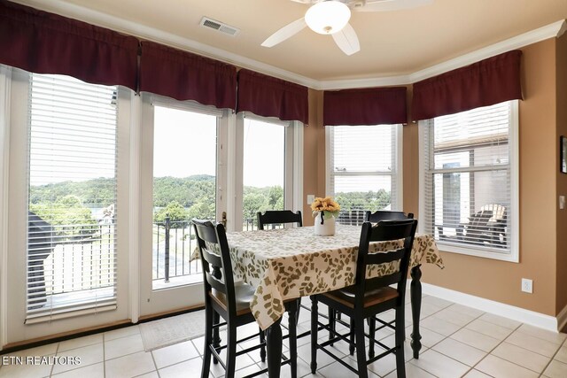 tiled dining space featuring crown molding and ceiling fan