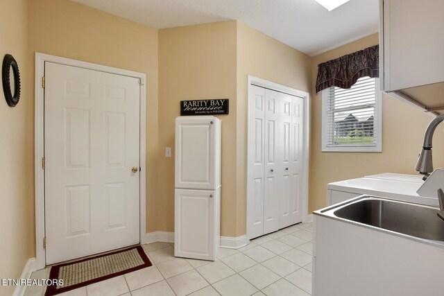 laundry room featuring cabinets, light tile patterned flooring, sink, and independent washer and dryer