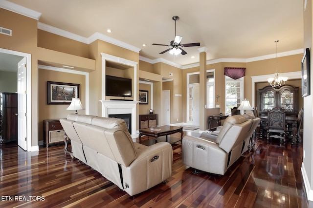 living room with dark wood-type flooring, ornamental molding, and ceiling fan with notable chandelier