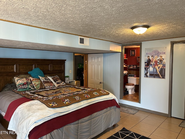 bedroom featuring wood walls, crown molding, light tile patterned floors, a textured ceiling, and connected bathroom