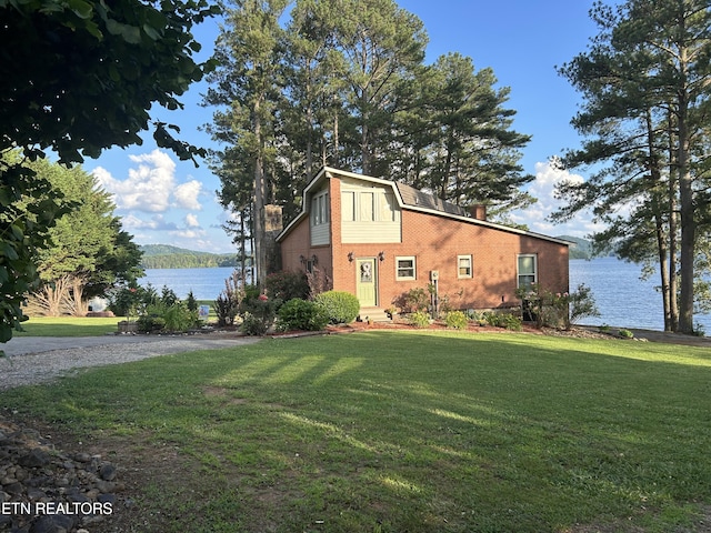 view of side of home featuring a water view and a lawn