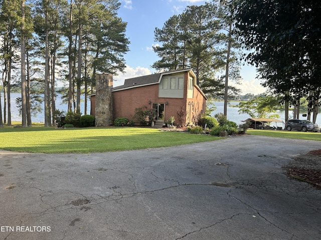 view of side of home featuring a yard and a water view