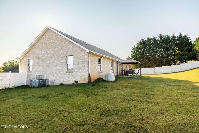 view of side of property with central air condition unit, a yard, and a gazebo