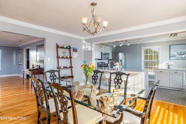 dining room featuring crown molding, light hardwood / wood-style flooring, a notable chandelier, and sink