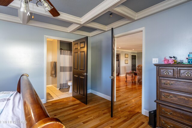 bedroom with crown molding, light hardwood / wood-style floors, beamed ceiling, coffered ceiling, and connected bathroom