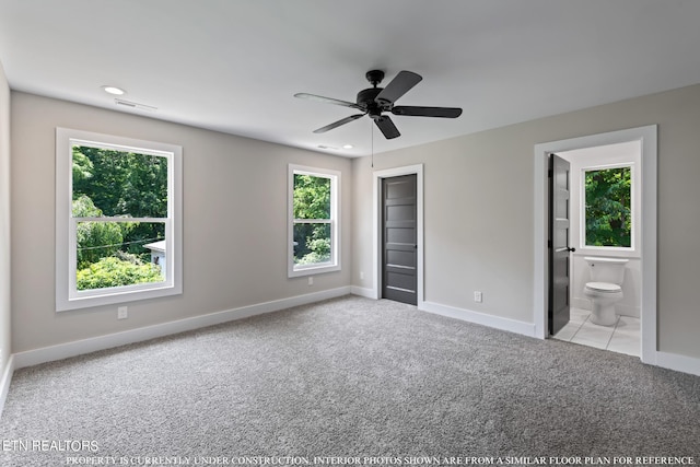 unfurnished bedroom featuring a closet, light colored carpet, connected bathroom, and ceiling fan