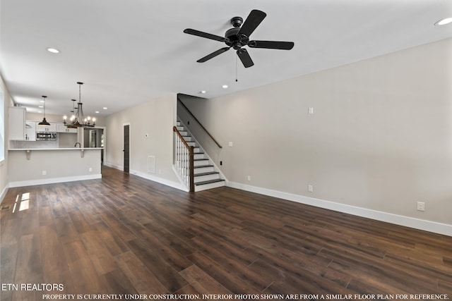 unfurnished living room featuring dark hardwood / wood-style floors and ceiling fan with notable chandelier