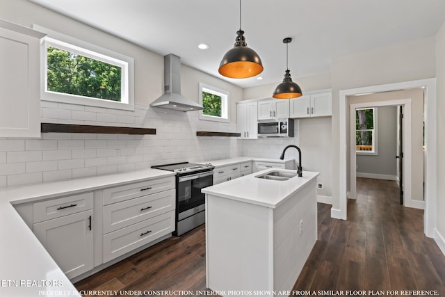 kitchen with a kitchen island with sink, wall chimney range hood, sink, white cabinets, and appliances with stainless steel finishes